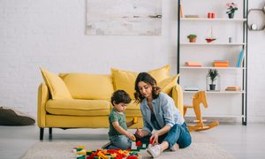 A mom and toddler playing a game in the living room.