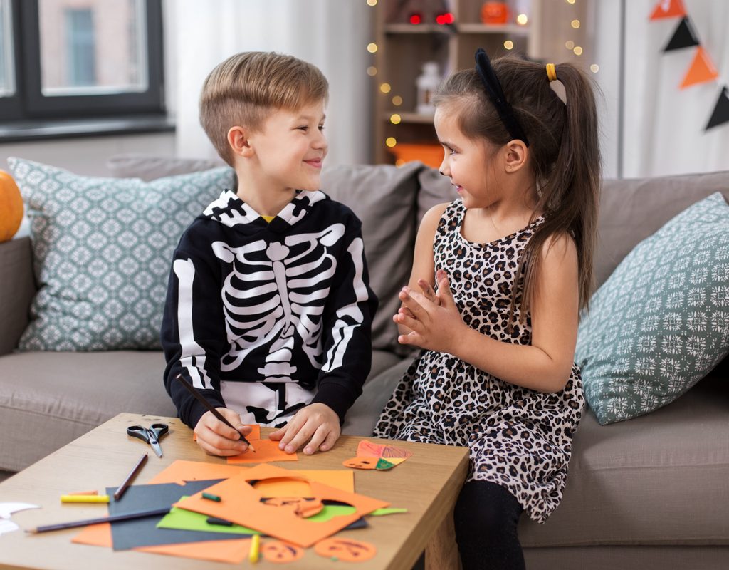 Two young kids doing a Halloween craft together.