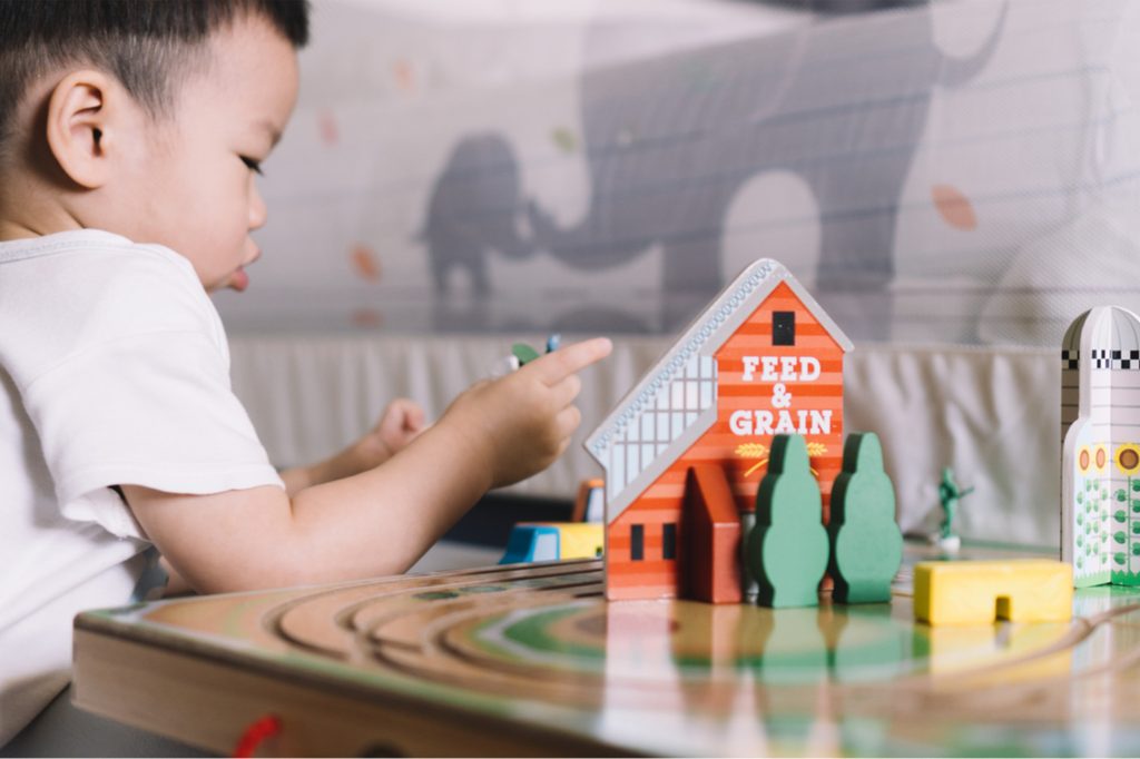 Toddler boy playing with toy farm