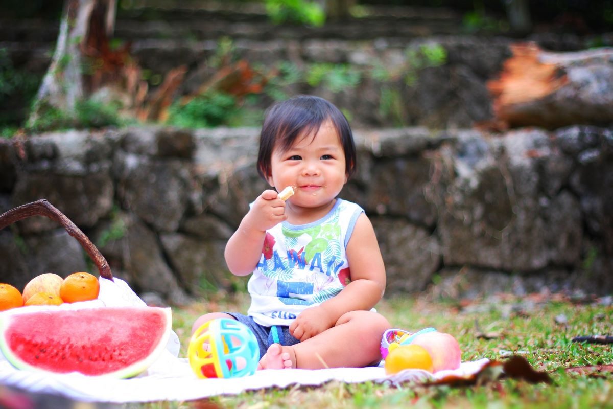 baby sitting on picnic blanket eating