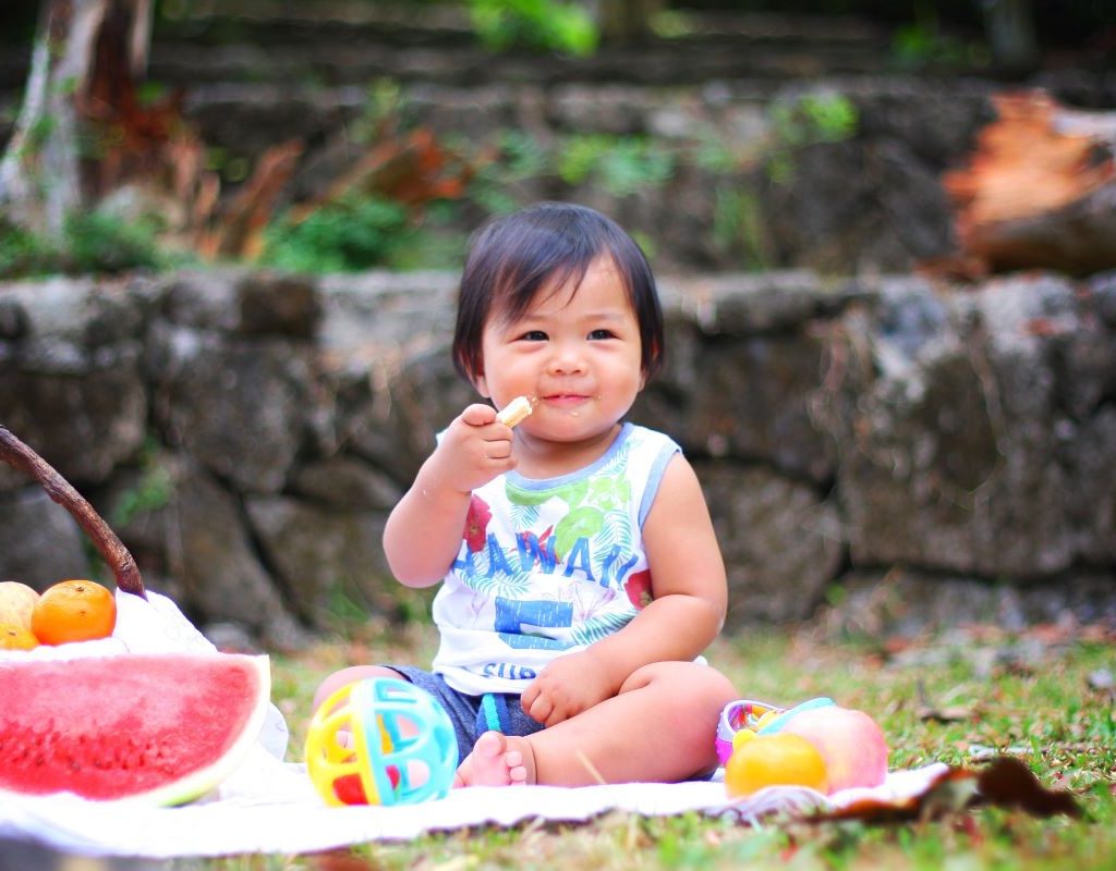 baby sitting on picnic blanket eating