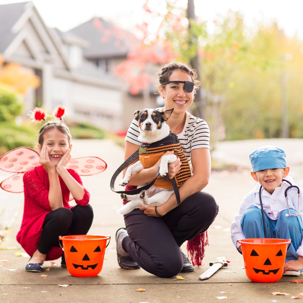 A mom and her kids and dog out trick-or-treating.