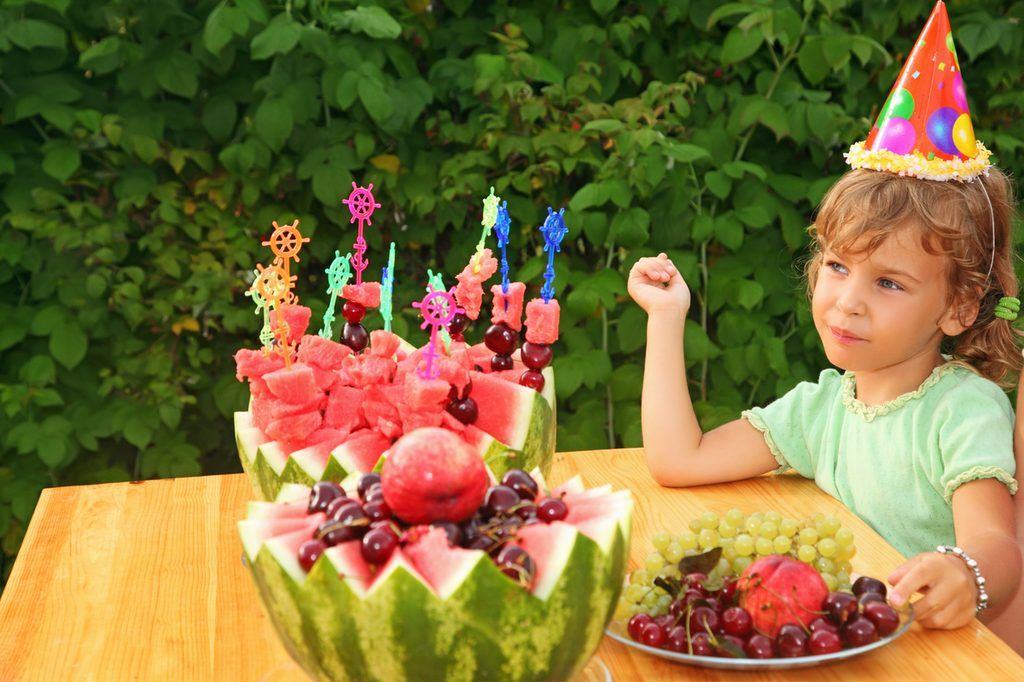 Little girl having a healthy fruit cake at her birthday party
