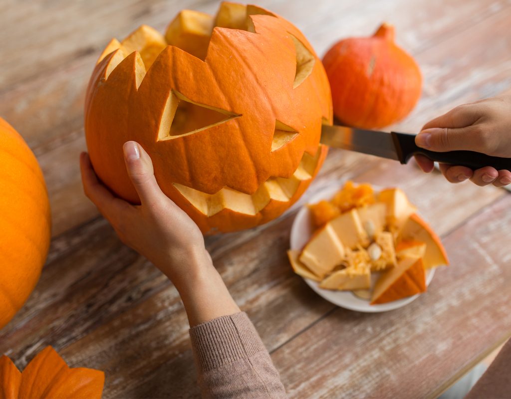 adult carving a pumpkin