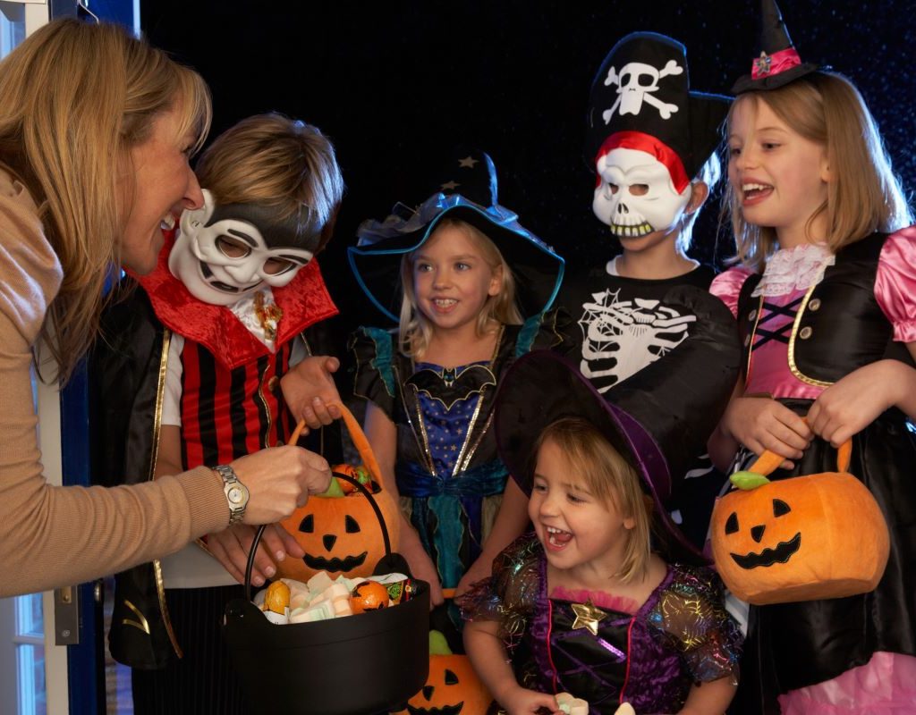 Kids in various costumes receiving trick or treat candy