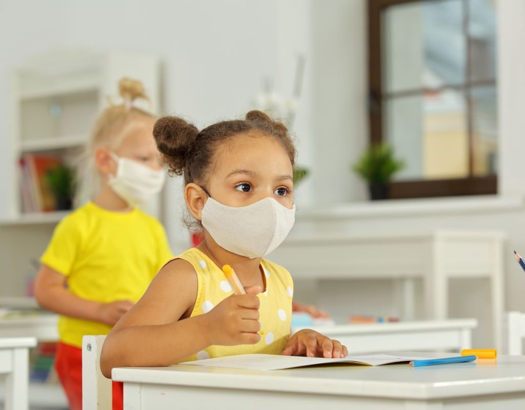Little girl sitting in class wearing a mask
