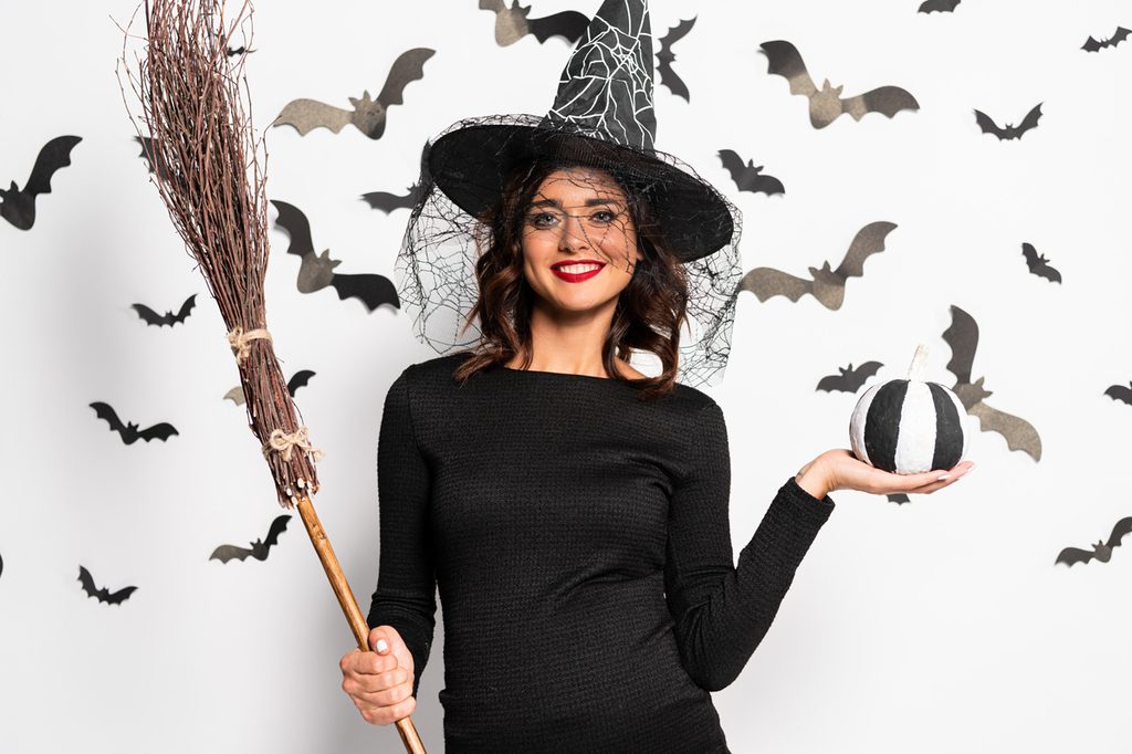 Happy pregnant mom wearing a maternity witch costume for Halloween