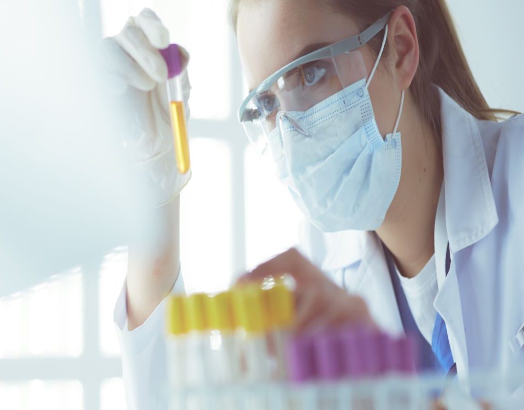 scientist holding dropper over test tubes