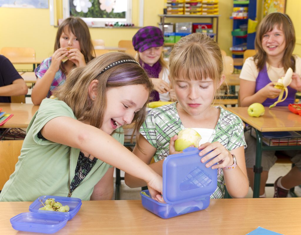 Kids at lunch looking at each other's lunches.