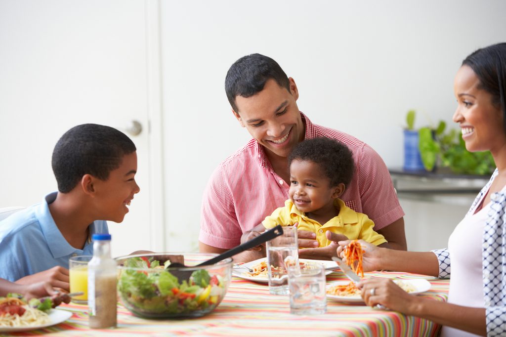 A family with a toddler sitting down to dinner.