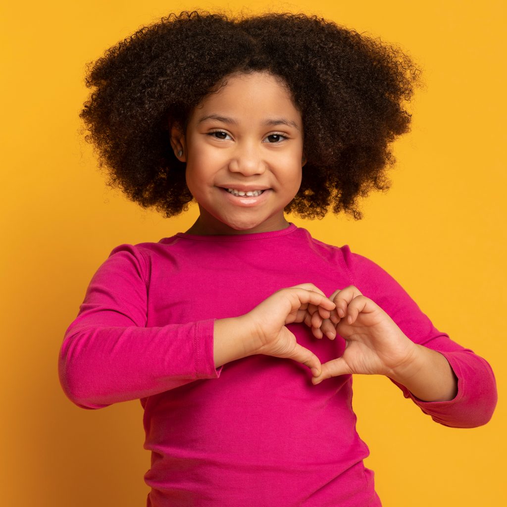 A girl making a heart with her hands.