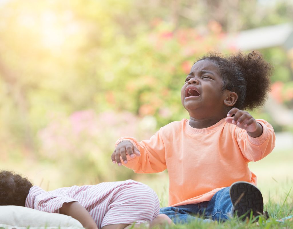 A toddler throwing a tantrum outside.
