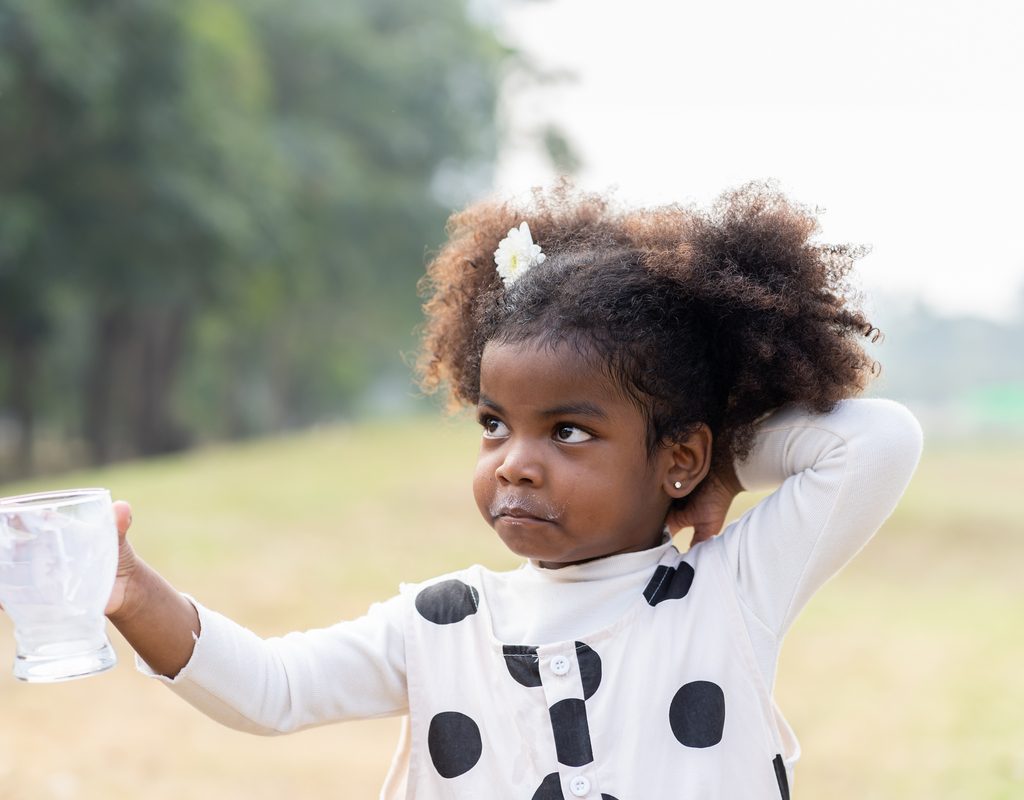 A little girl who finished drinking a glass of milk.