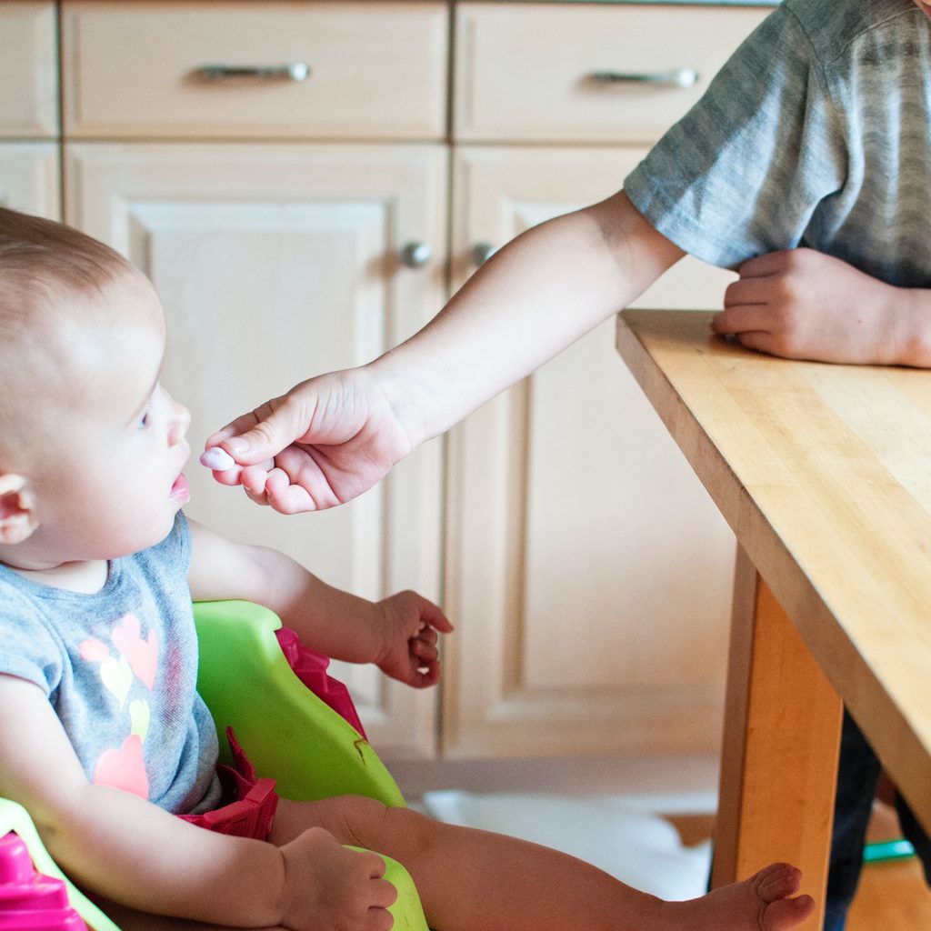 A sibling feeding little baby