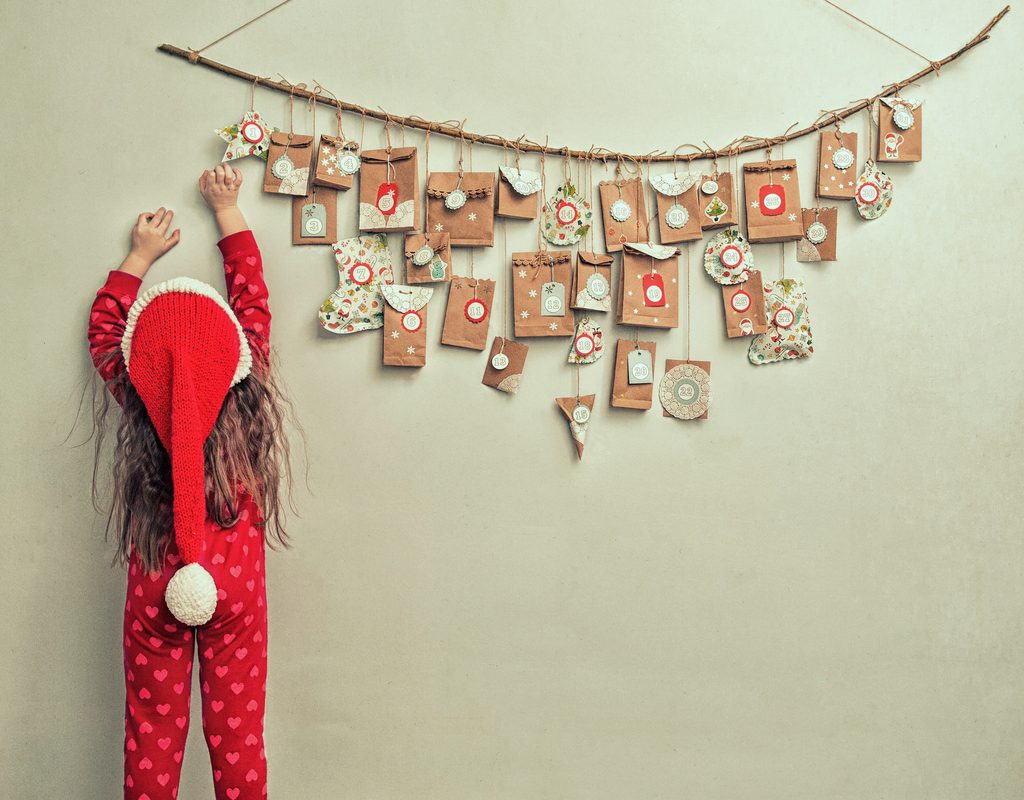 little girl reaching for a hanging advent calendar