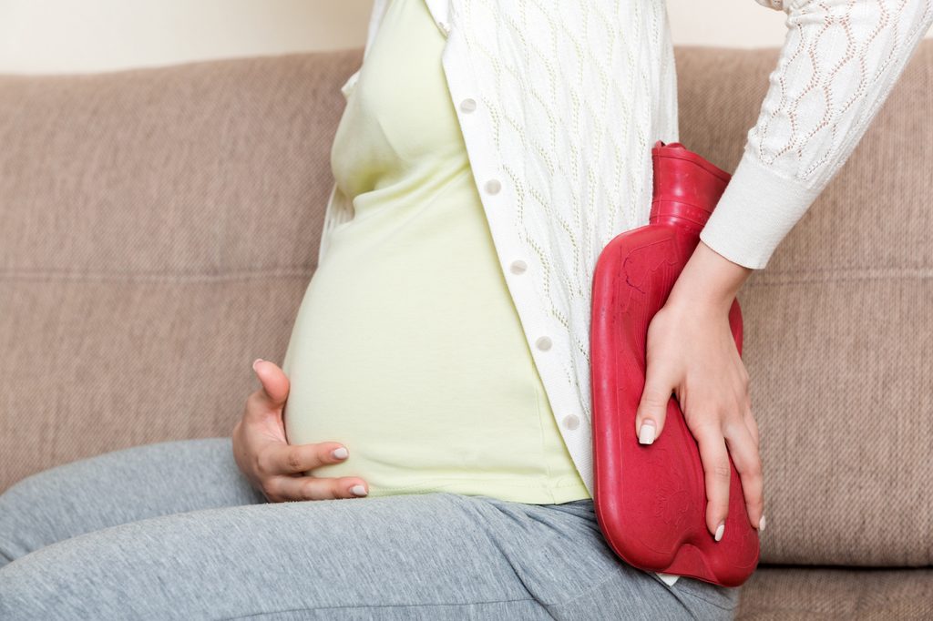Pregnant woman using heating pad hot water bottle