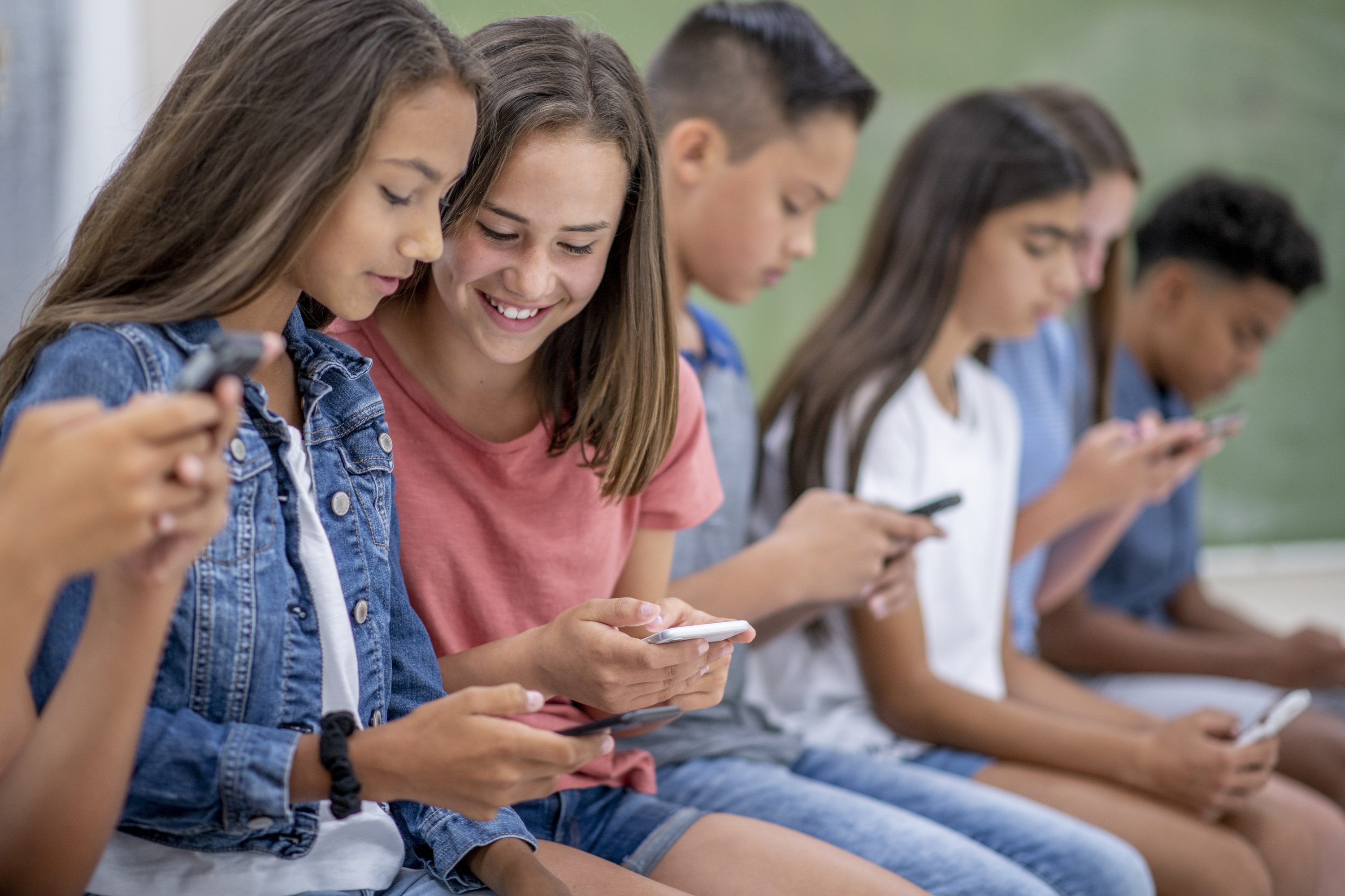 A group of teens on their phones.