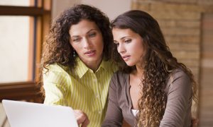 A parent helping their teen on the laptop.