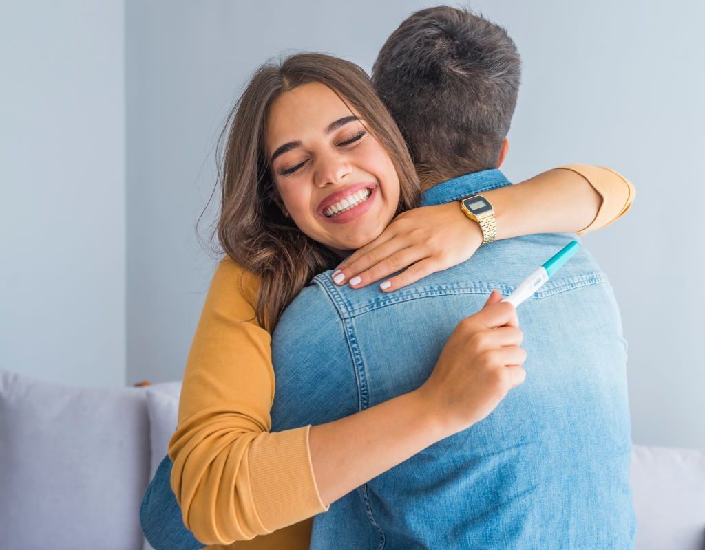 Couple hugging after looking at pregnancy test result