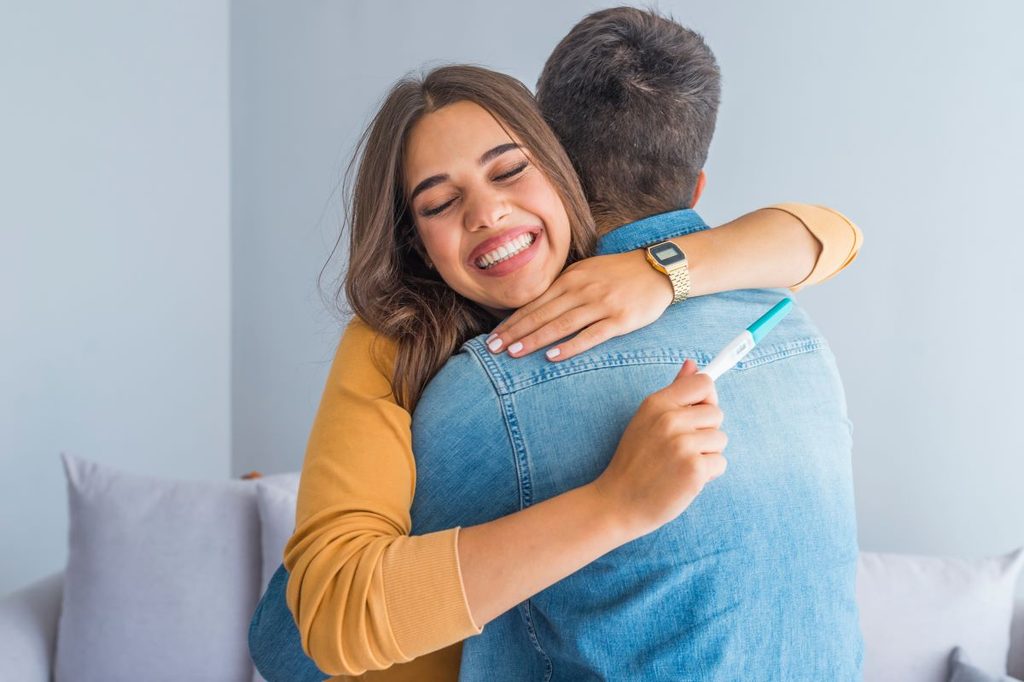 Couple hugging after looking at pregnancy test result