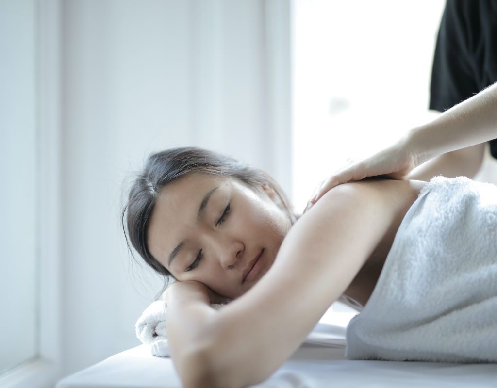 A lady lays face down on massage table getting a massage