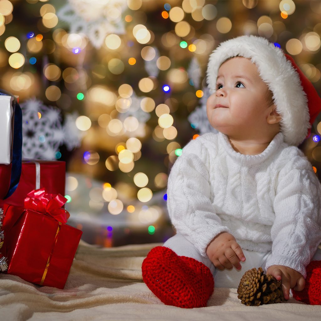 happy baby by the tree surrounded by holiday magic