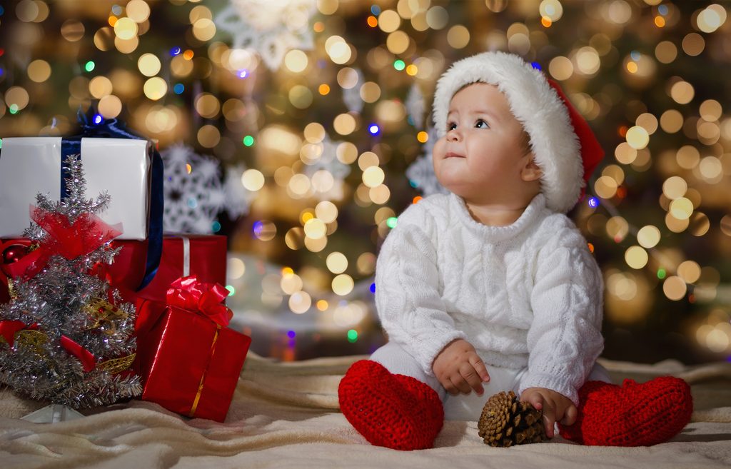happy baby by the tree surrounded by holiday magic