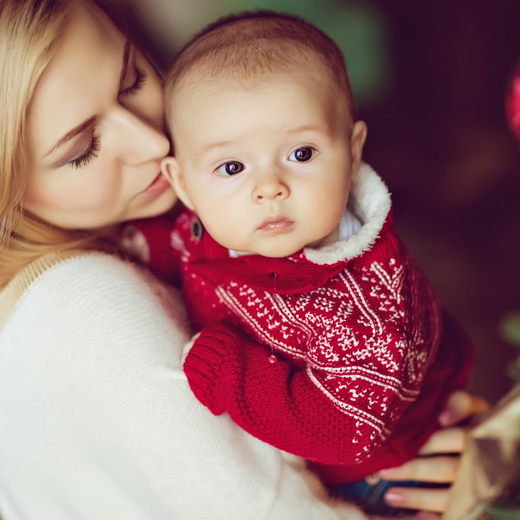 Mom holding baby wearing a Christmas sweater