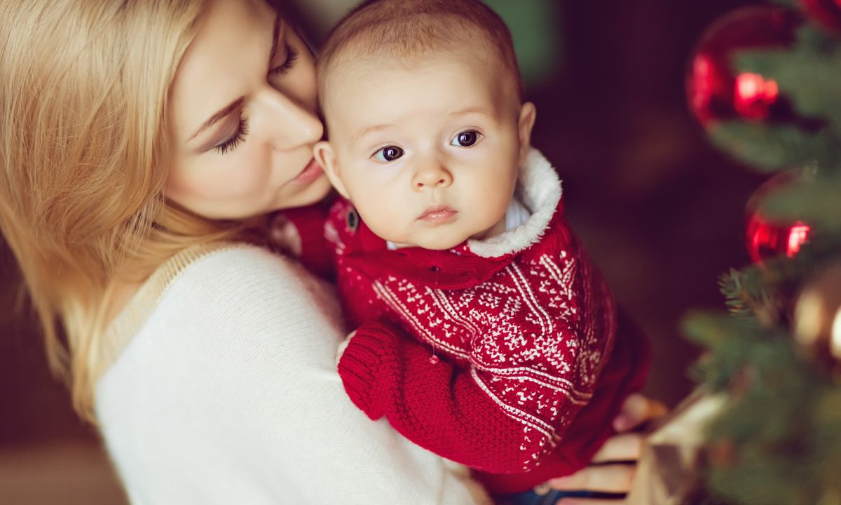Mom holding baby wearing Christmas sweater