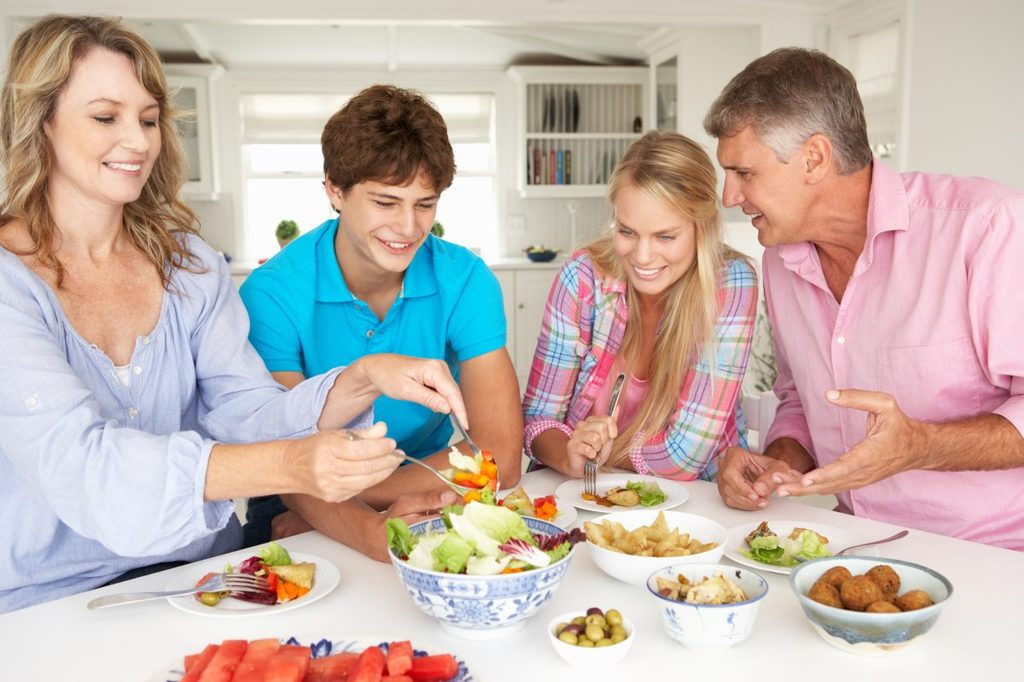Teens eating dinner with their parents.