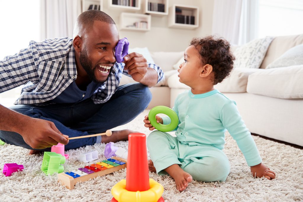 Toddler and dad having fun playing with toys on the floor.