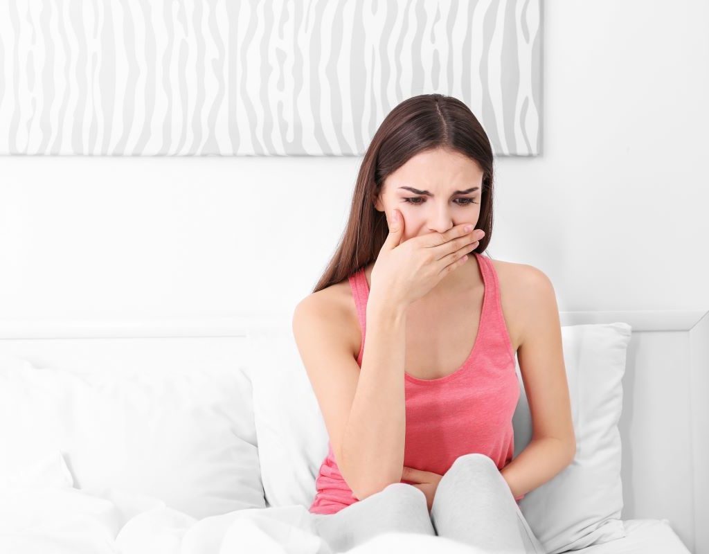 Young woman sitting on a couch covering her mouth