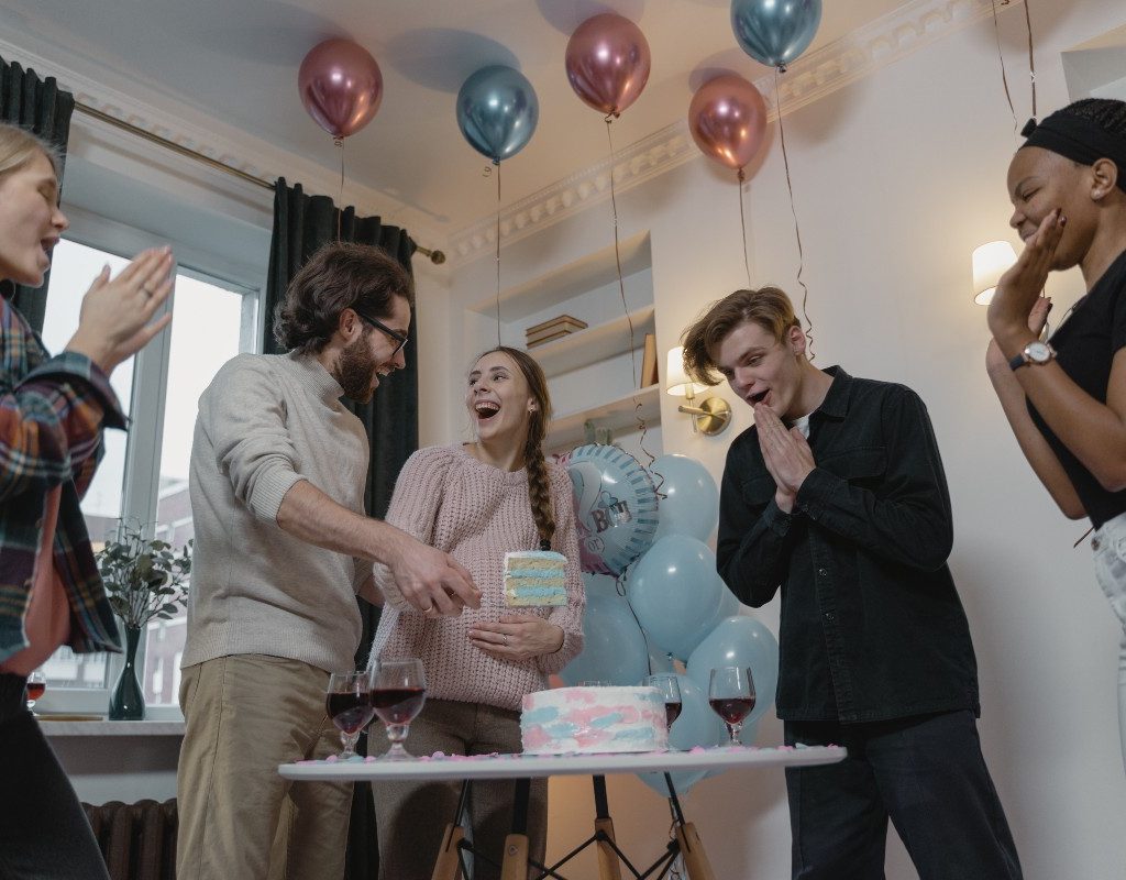 a couple cutting into a cake during a gender reveal party