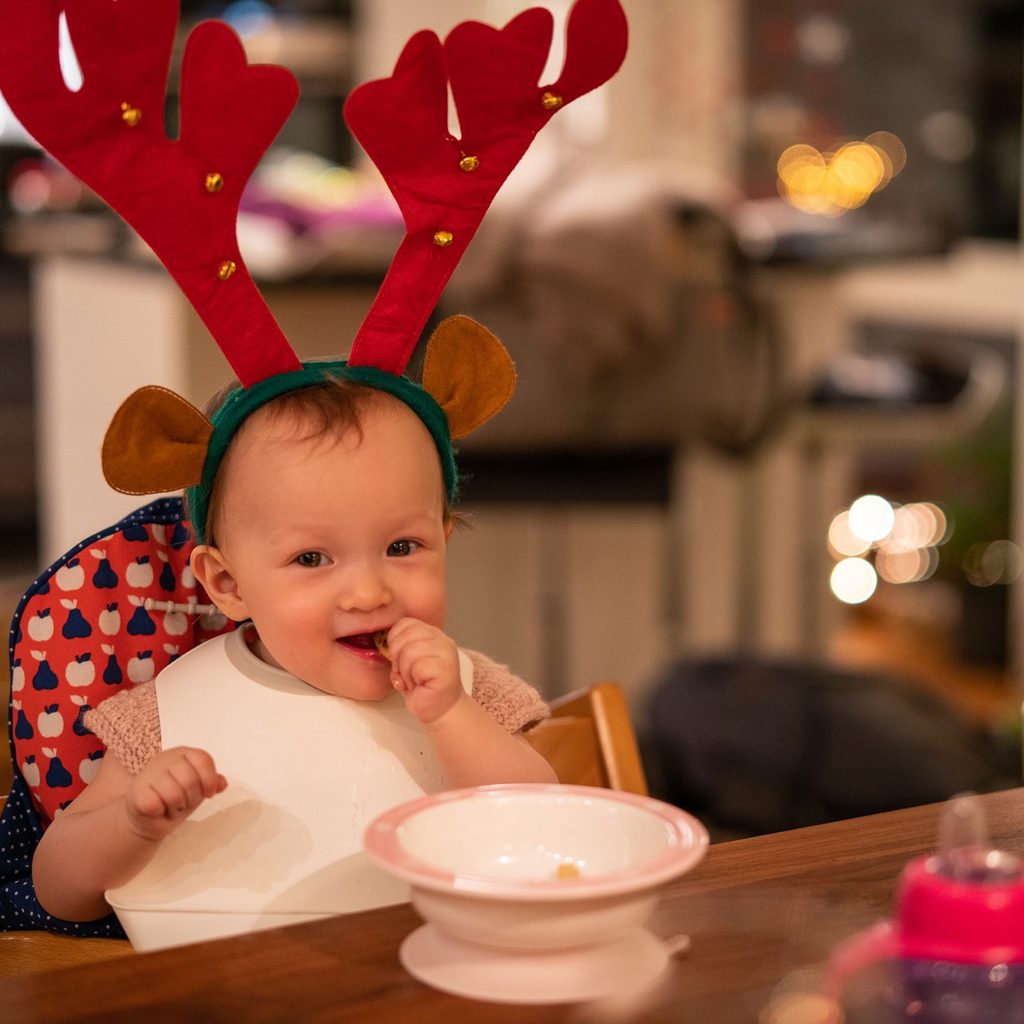 Baby eating in a reindeer hat