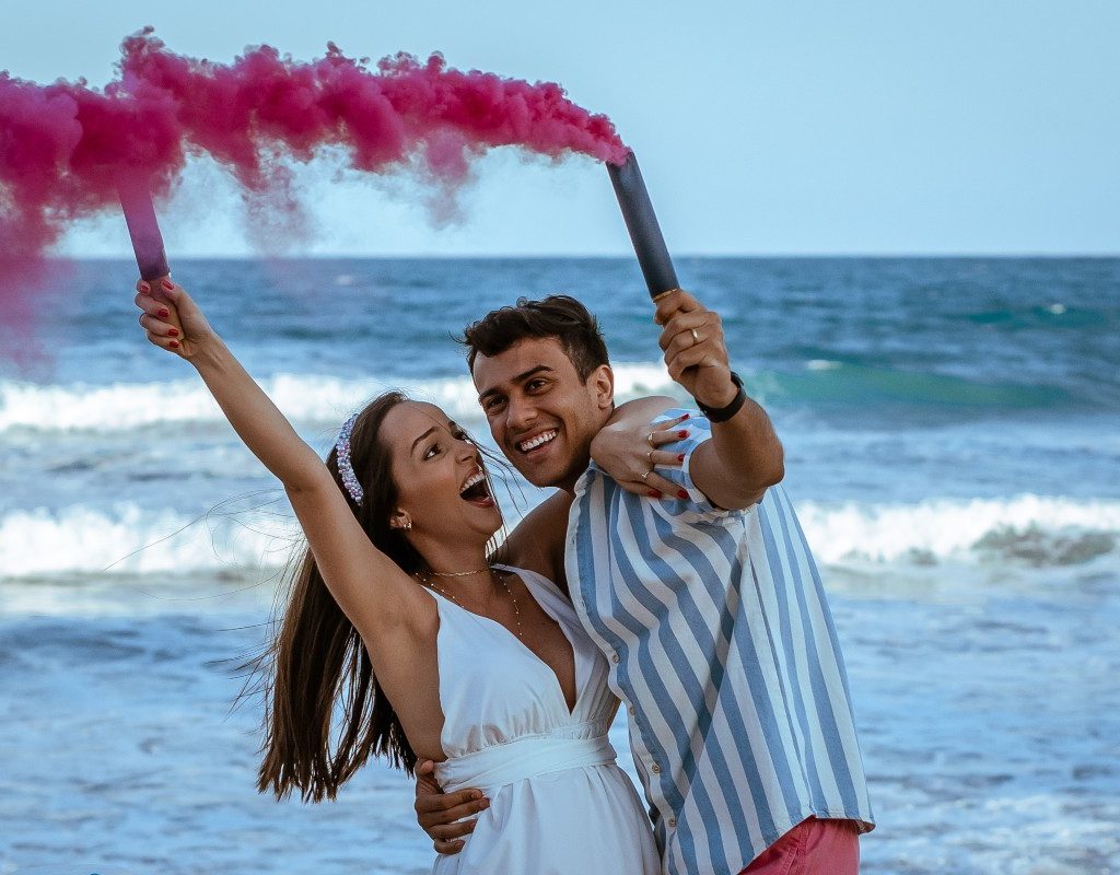 a couple on a beach celebrating gender reveal of a girl