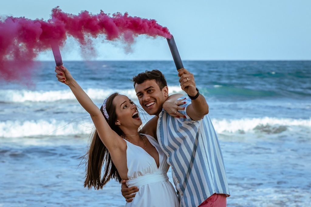 a couple on a beach celebrating gender reveal of a girl