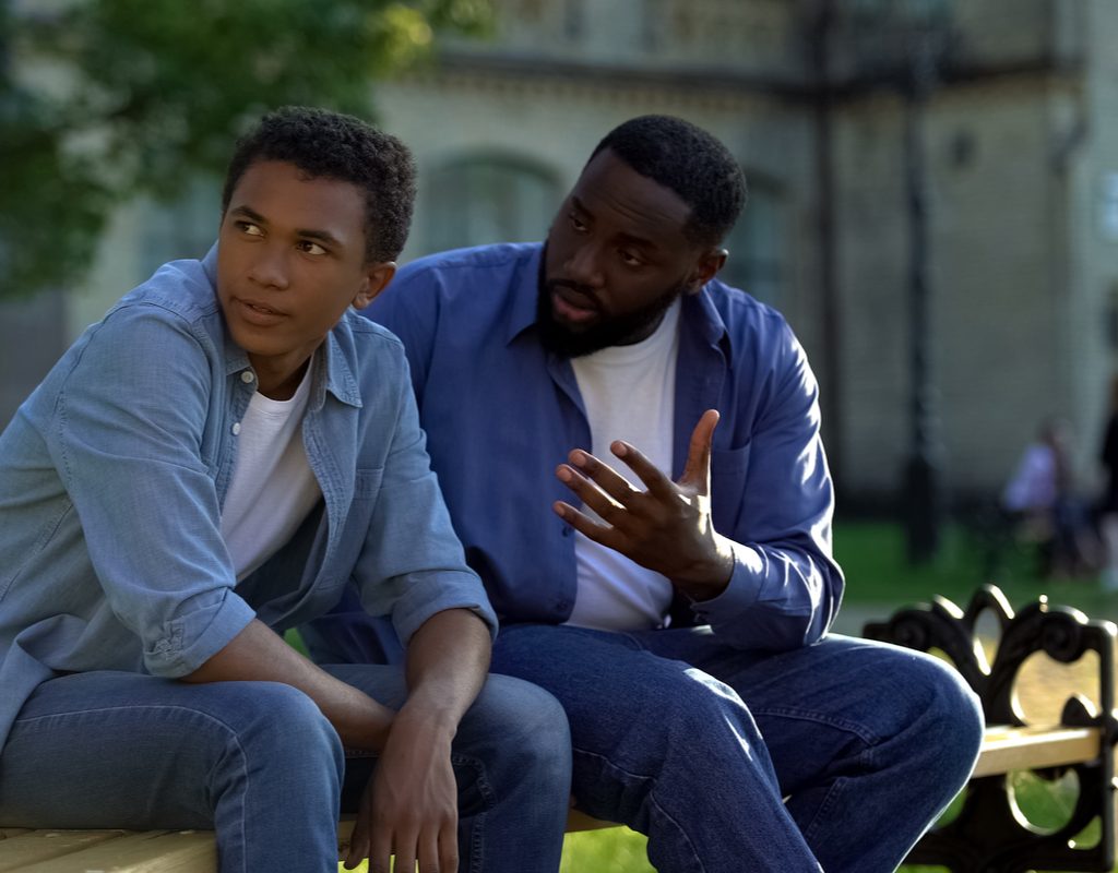 Father and teen having a talk on a bench