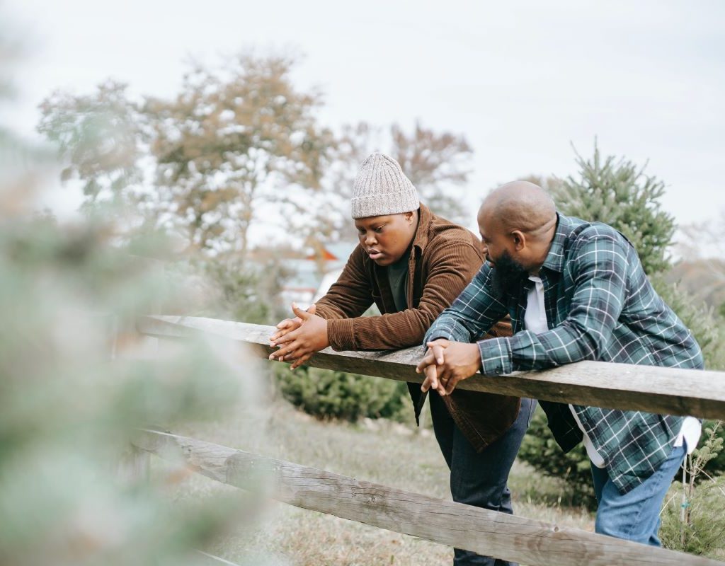 Father and son standing by fence talking