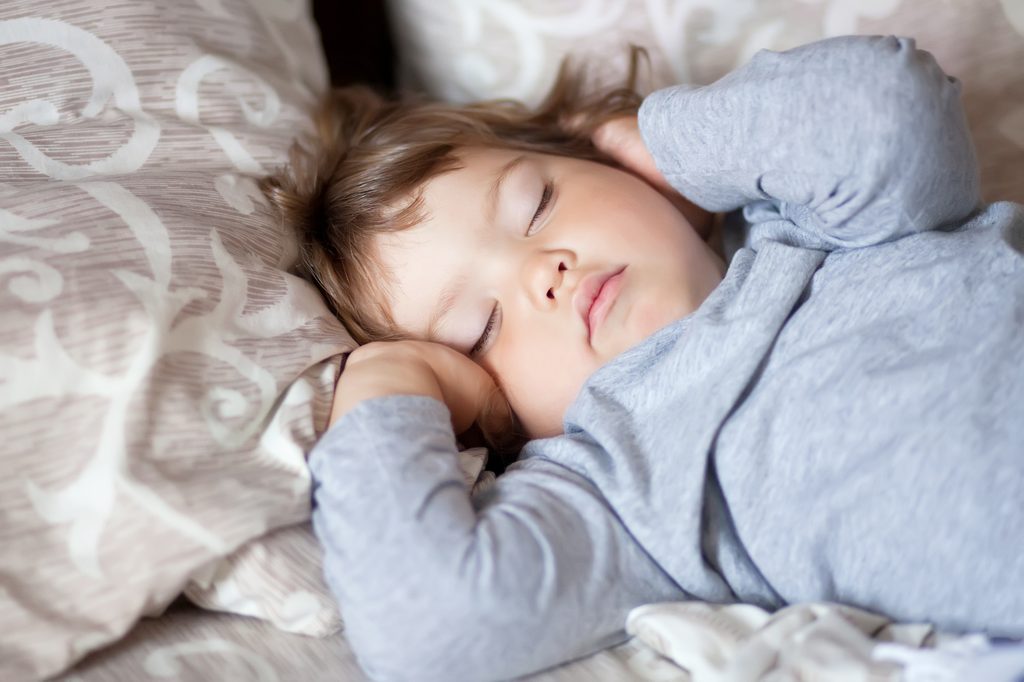 Toddler in bed sleeping.