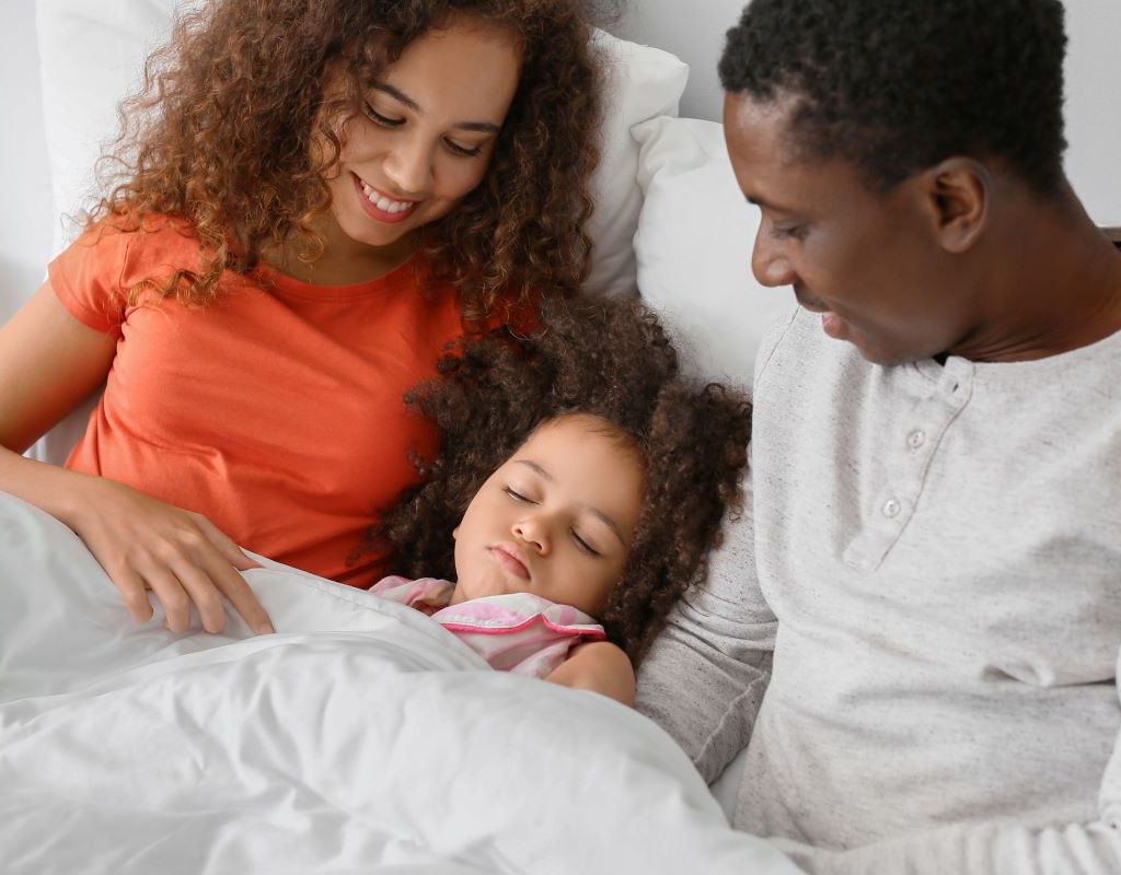 Little girl sleeping between parents in bed