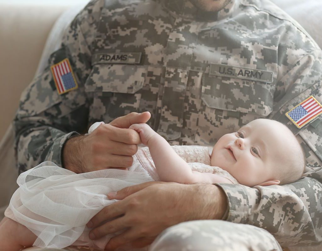 Military dad in uniform holding baby girl