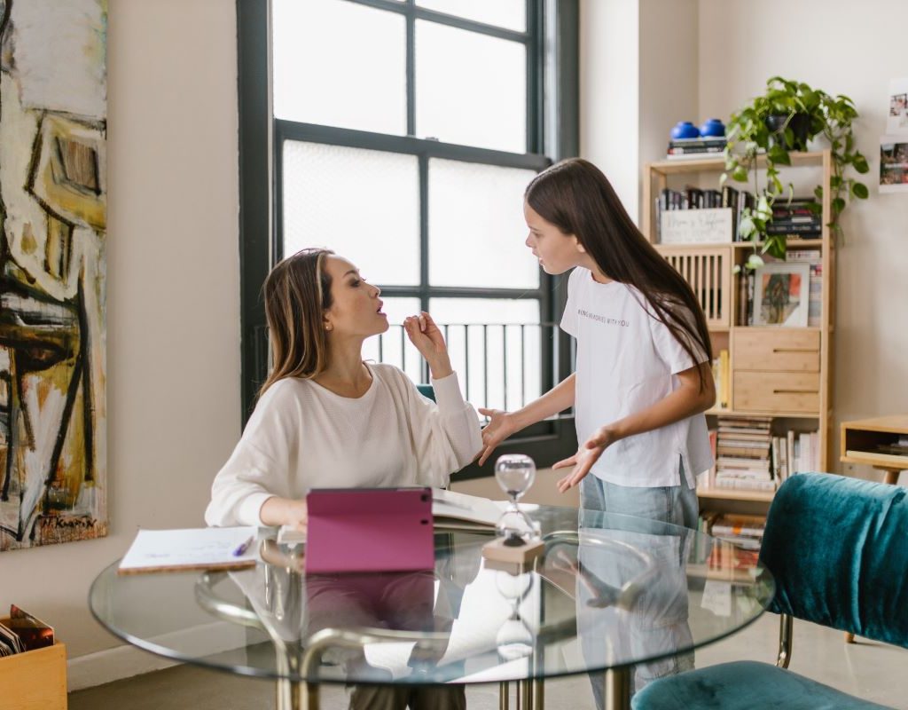 Mom sitting at table talking to daughter