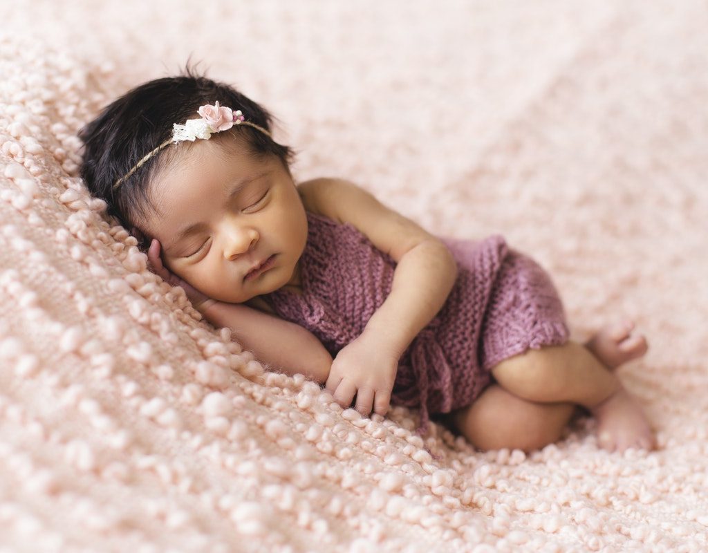 Newborn girl sleeping on a pink blanket.