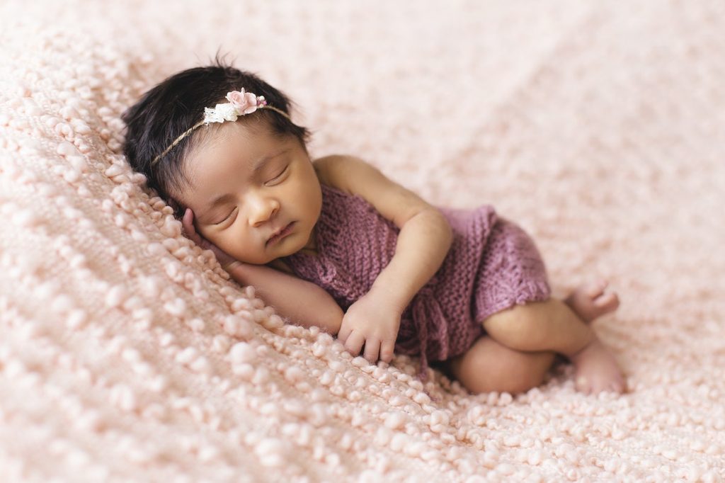 Newborn girl sleeping on a pink blanket