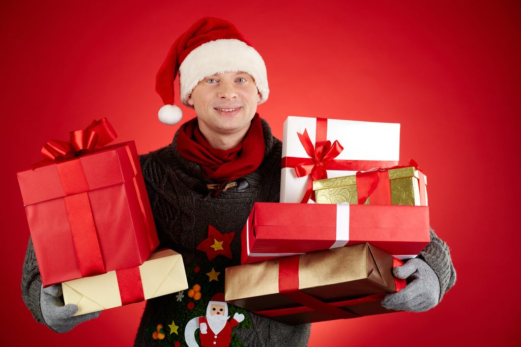 A young man holding Christmas packages.