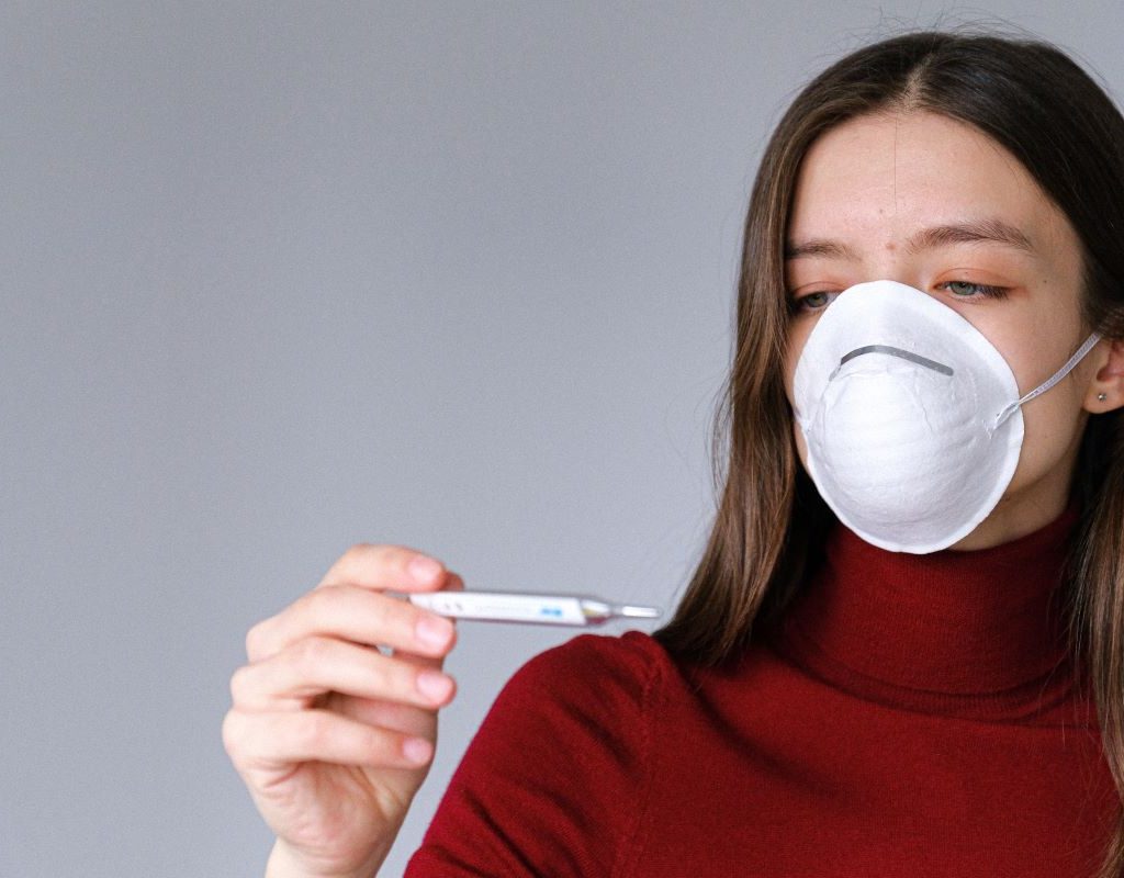 Girl with mask looking at thermometer