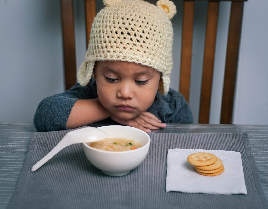 A toddler not wanting to eat their food.