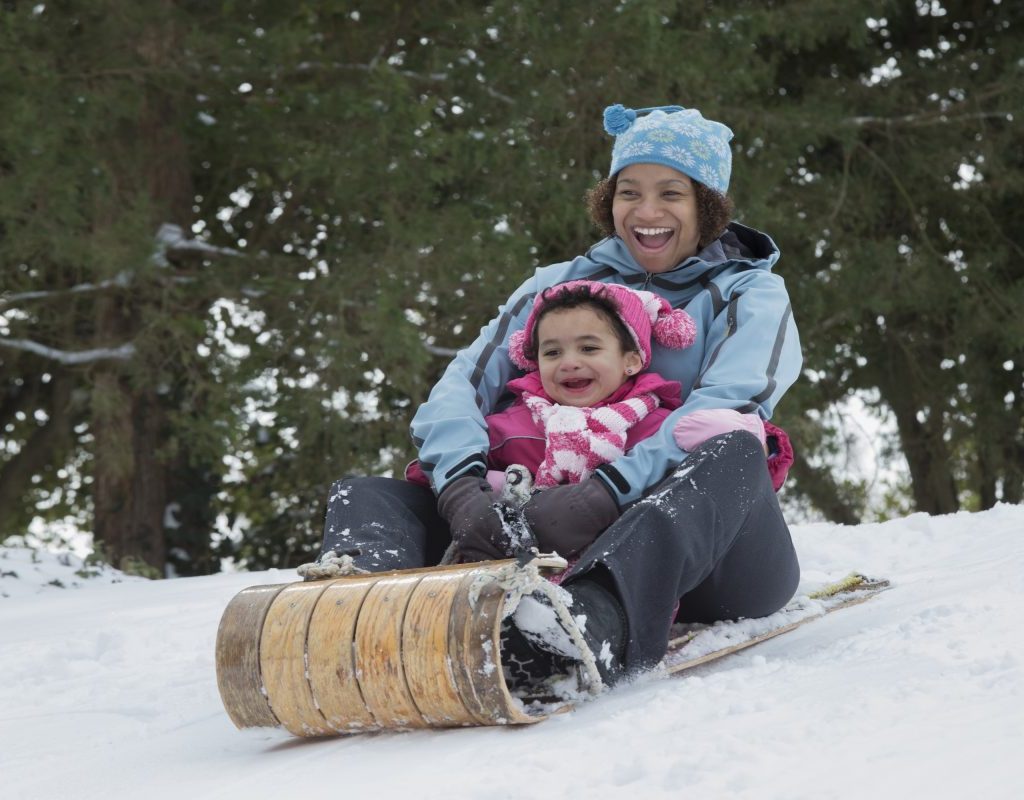 A mother and child sledding down a hill