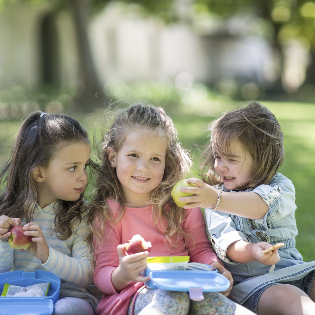 Toddler girls in a garden sharing lunch