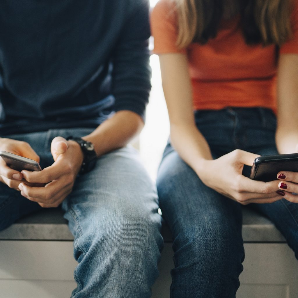 Boy and girl looking at their cell phones